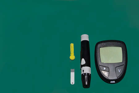 Kit for measuring blood glucose, with band and finger punch on green background
