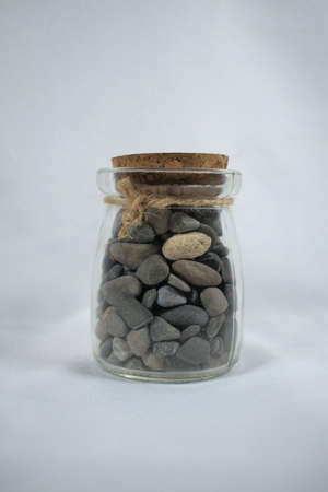 glass jar filled with stones closed with cork and stringの写真素材