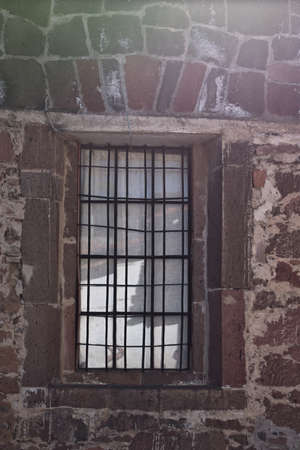 Window with black grille of a house made of stonesの写真素材