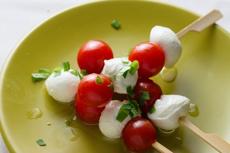 Caprese salad in the form of skewer made from cherries of mozzarella cheese, cherry tomatoes, basil...