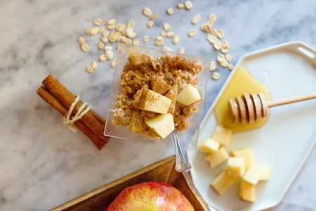 Top down view on oatmeal porridge breakfast with apples, cinnamon and honey on marbel surfaceの写真素材