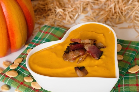 Cream pumpkin soup in white heart shaped bowl in rural country settingの写真素材
