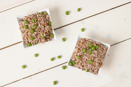 Top down view on two square bowls of boiled buckwheat and peasの写真素材