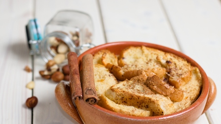 earthenware pot of bread and butter pudding with spilled glass jar of walnutsの写真素材