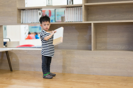 A boy is choosing a book from a shelf.の写真素材