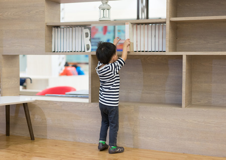 A boy is choosing a book from a shelf.の写真素材