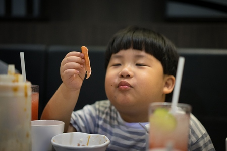 A fat boy is eating bacon.の写真素材