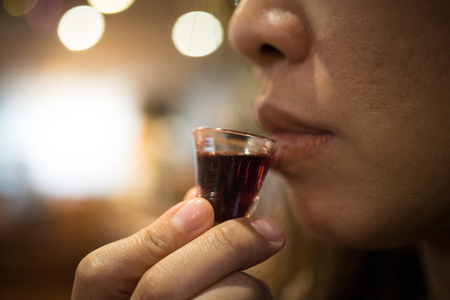 A believer is drinking a cup of red wine in a Holy Communion.