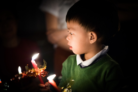 A boy ignite a candle in the darkness.の写真素材