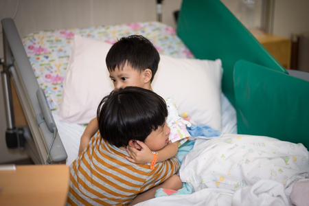 A big brother hugs his sick brother in the hospitalの写真素材