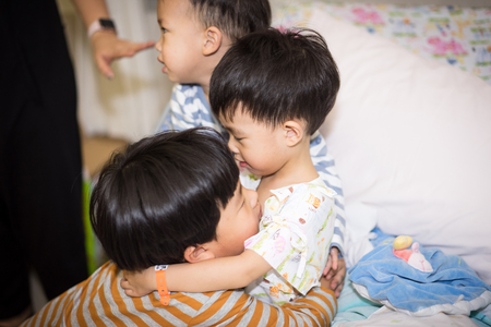 A big brother hugs his sick brother in the hospitalの写真素材