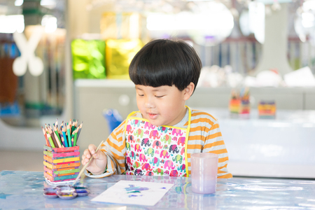 A boy is painting in the study room.の写真素材