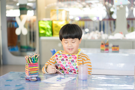 A boy is painting in the study room.の写真素材
