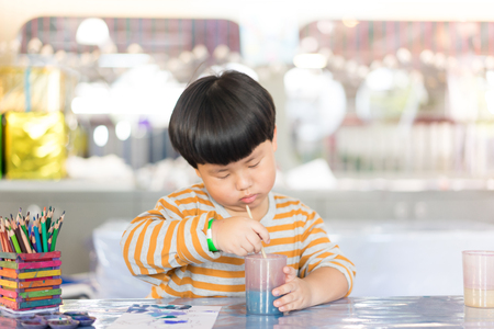 A boy is boring when he painting in the study room.の写真素材