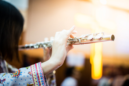 A woman is playing hymn song by her flute in the church.の写真素材