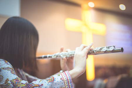 A woman is playing hymn song by her flute in the church.の写真素材