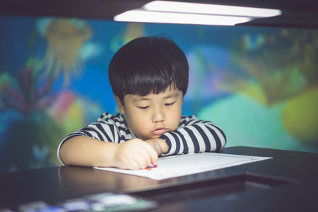 A boy is painting with low light in the dark room.の写真素材