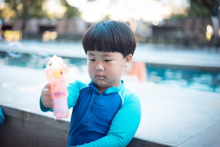 A happy asian boy is playing at the pool.