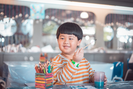 A boy is painting in the study room.の写真素材