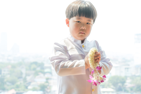A boy wearing Thai dress, holding garland for give thanks his parents in Songkran day, Thai New Year day.の写真素材