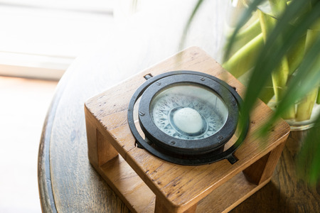 The vintage compass on the wood table with the sun light.の写真素材