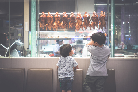 2 hungry brothers are watching a chef preparing roasted duck in Chinese restaurantの写真素材