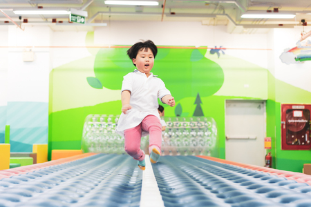 Brothers are running and jumping on the soft runway in a playground.の写真素材