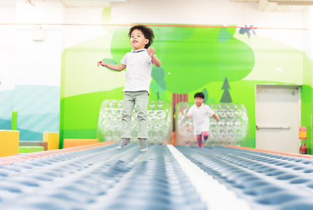 Brothers are running and jumping on the soft runway in a playground.の写真素材