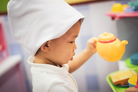 A little chef is playing a food and tea pot toy at the playground.の写真素材