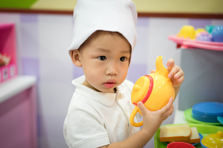 A little chef is playing a food and tea pot toy at the playground.の写真素材