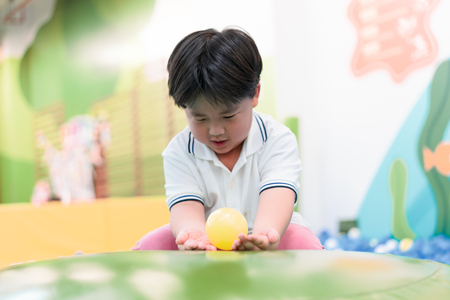 A boy is playing plastic balls on the wind hole at a playground.の写真素材