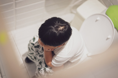A boy is sitting on toilet with suffering from constipation or hemorrhoid.の写真素材