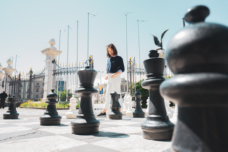 A business woman is thinking about strategy to win in the giant chess game at Europe garden.の写真素材