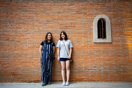 Beautiful modern girls near the orange brick wall. Youth hipster style. Fashion shoot.の写真素材