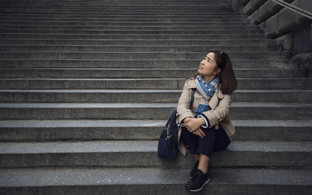 A smart woman sitting at the concrete ladder in the Europe park.の写真素材