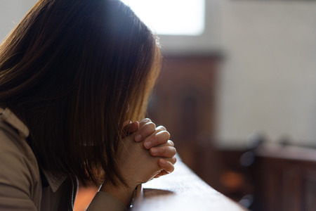 A Christian girl is sitting and praying with humble heart in the church.の写真素材
