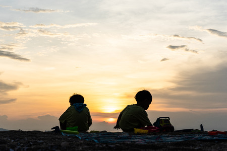 The silhouette brothers are playing together at the beach in evening.の写真素材