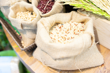 Grains, beans, grains and rice in a calico bag on a wooden table. The dried rice is a component.の写真素材