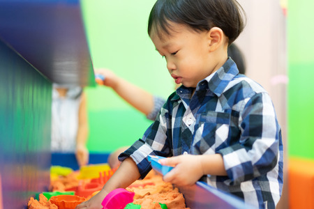 A boy is playing science sand at the indoor playground.の写真素材