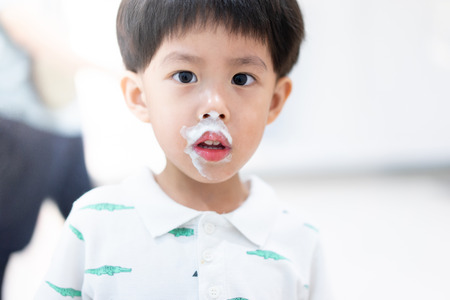 A happy boy is eating delicious ice-cream with sloppy mouth.の写真素材