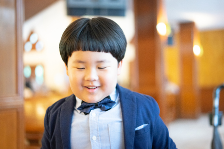 A naughty boy makes funny face, he is playing In the church with formal suit.の写真素材
