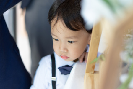 A shiny boy is waiting his father in the church with formal suit.の写真素材