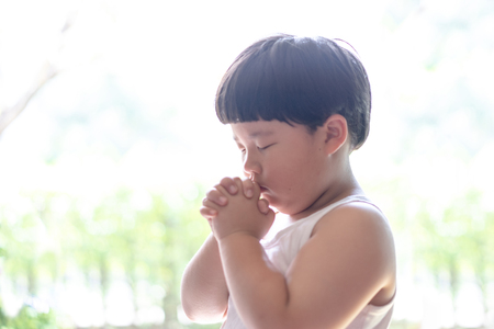 A little prayer, A fat boy is praying seriously and hopefully to Jesus in the morning.の写真素材