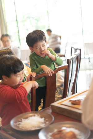 Kids are watching the chef is cutting the duck skin from the Beijing duck with a very sharp knife in a famous Chinese restaurant at the Chinese new year season.の写真素材
