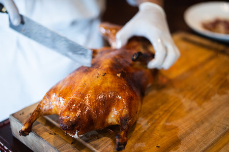 The chef is cutting the duck skin from the Beijing duck with a very sharp knife in a famous Chinese restaurant at the Chinese new year season.の写真素材