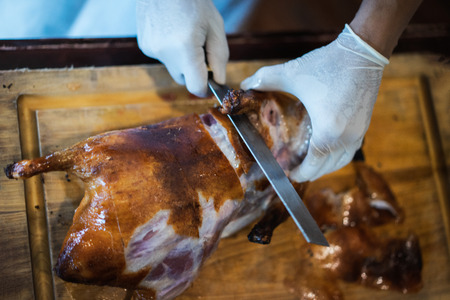 The chef is cutting the duck skin from the Beijing duck with a very sharp knife in a famous Chinese restaurant at the Chinese new year season.の写真素材
