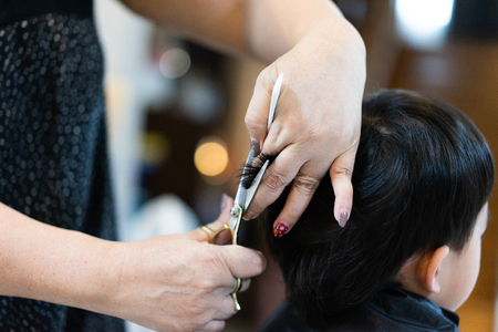 Grandmother is cutting hair of her cute grandson at home.の写真素材