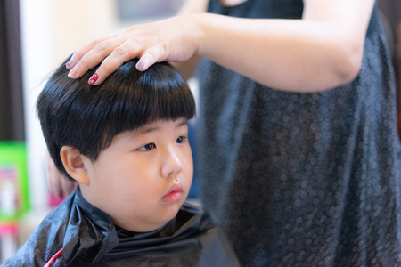 Grandmother is cutting hair of her fat grandson at home.の写真素材