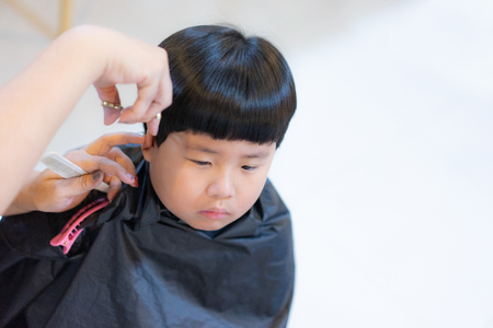 Grandmother is cutting hair of her fat grandson at home.の写真素材