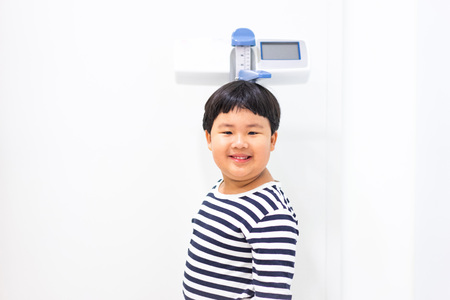 A fat boy is measuring his height and his weight himself in hospitalの写真素材